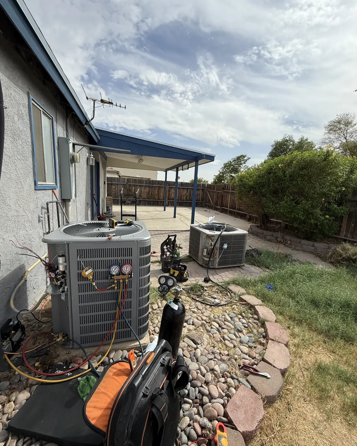 Refrigerant gauges connected to an outdoor AC unit during an Elevate repair